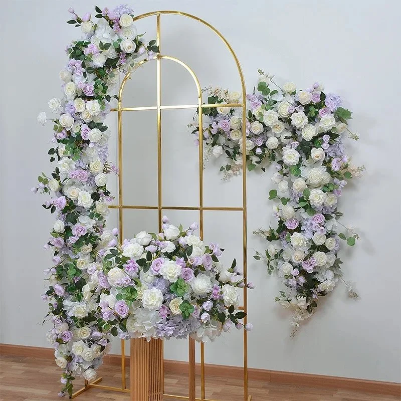 Elegant floral arrangement with white and purple roses on a gold metal arch, placed indoors on a wooden floor.
