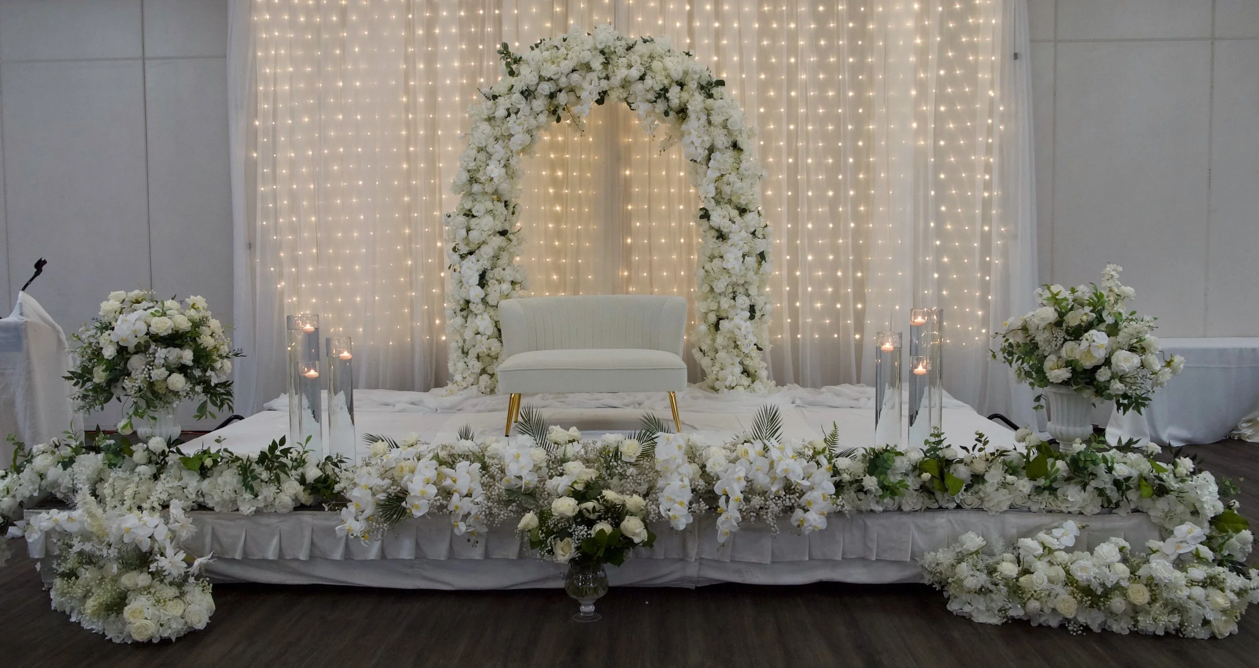 Elegant wedding stage with white flowers, arch, and candles